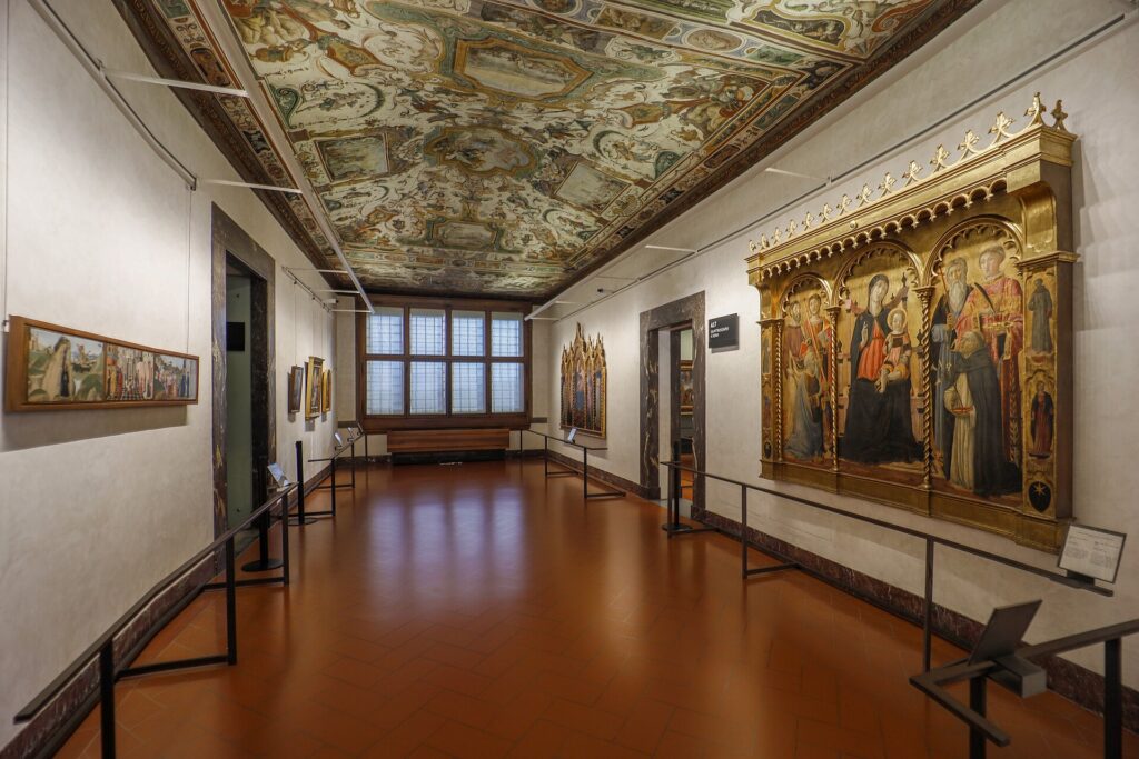 A room in the Uffizi Gallery, Florence, gilded altarpieces below a frescoed ceiling